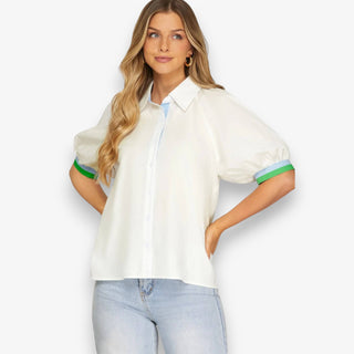 Woman wearing a white blouse with green and blue accents on a plain background