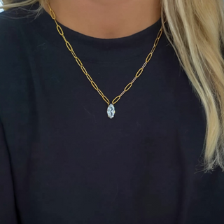 Gold chain necklace with a clear pendant on a dark background