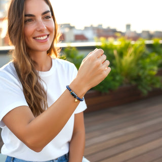 Woman wearing a bracelet on a rooftop with greenery in the background