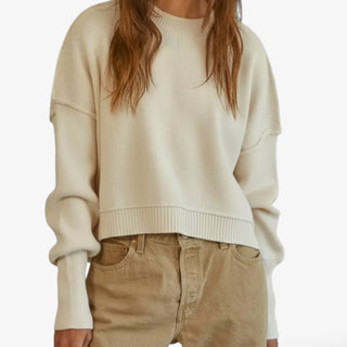 Person wearing a beige sweater and beige pants on a white background
