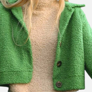Close-up of a green textured jacket with a button on a neutral background