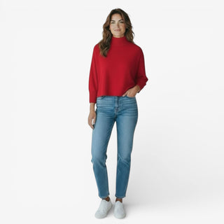 Woman wearing a red sweater and blue jeans on a white background