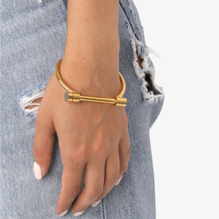 Gold bracelet on a wrist with denim background