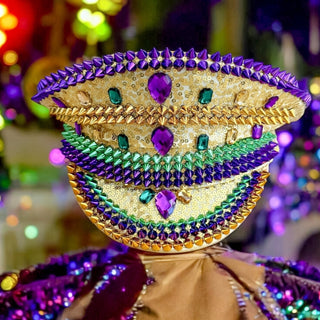 Colorful beaded conductor hat with purple, green, and gold colors against a blurred festive background.