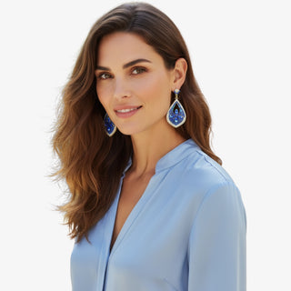Woman wearing blue earrings with a light blue top on a white background