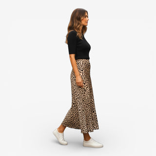 Woman wearing a black top, leopard print skirt and white sneaker's on a white background