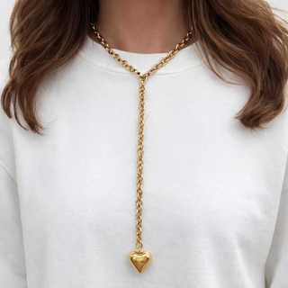 Woman wearing a gold necklace with a bubble heart. 