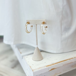 Transparent hoop earrings with gold glitter on a white stand with a white background