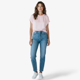 Woman wearing a pink t-shirt and blue jeans on a white background