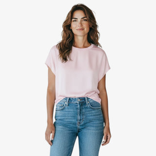 Woman wearing a light pink mixed media t-shirt and blue jeans on a white background