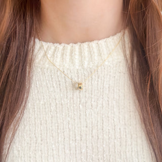 Close-up of a person wearing a delicate gold necklace with two small pendants.