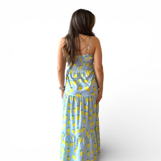 Woman wearing a blue dress with yellow lemon patterns on a white background