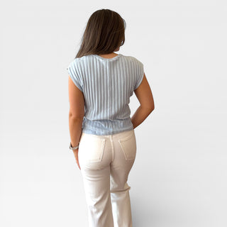 Person wearing a light blue striped shirt and beige pants against a white background