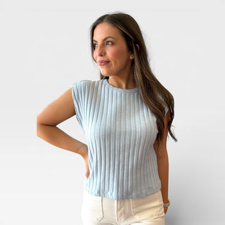 Woman wearing a light blue ribbed top against a white background
