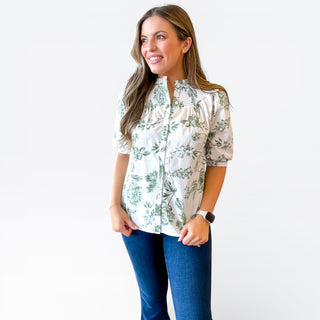 Woman wearing a floral blouse and blue jeans on a white background