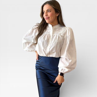 Woman wearing a white pintuck cotton blouse with puffed sleeves.
