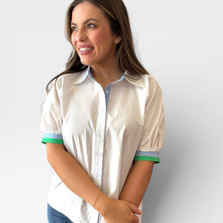 Woman wearing a white shirt with colorful cuffs against a plain background