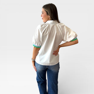 Back view of white blouse with puff sleeves and green trim, relaxed fit, styled with medium wash jeans against a clean background