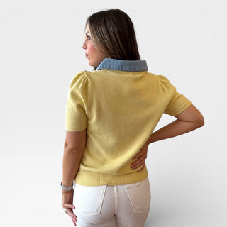 Woman wearing a yellow sweater with denim collar against a white background