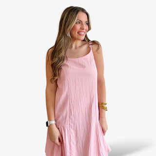 Pink sleeveless mini dress with button strap detail, lightweight crinkle fabric, relaxed fit, and flowy hem for an effortless spring and summer outfit.