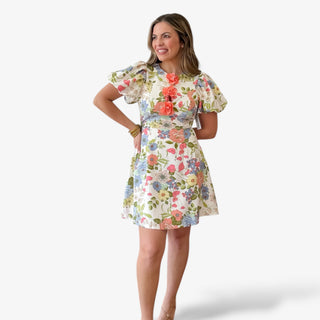 Floral print mini dress with multicolor flowers, short puff sleeves, fitted waist, and statement 3D floral appliqué neckline for a feminine spring and Easter outfit.
