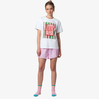 Woman wearing a white t-shirt with a graphic design and pink shorts on a white background