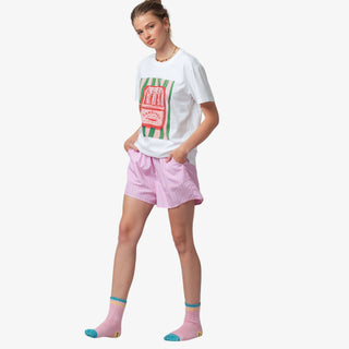 Person wearing a white t-shirt with colorful design and pink shorts on a white background