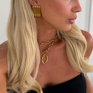 Gold ribbed stud earring worn by model on white background