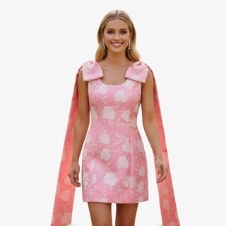 Pink jacquard bow mini dress with oversized shoulder bows and floral texture detail front view