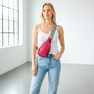 Fuchsia sling bag with pink and turquoise patterned strap styled as crossbody bag on model front view
