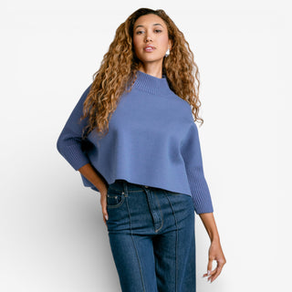 Woman wearing a blue sweater and jeans on a white background