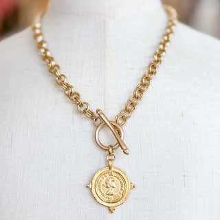 Kitzi Gold Coin Necklace in 18K gold-filled metal with chunky chain, front toggle closure and vintage-inspired round coin pendant, close-up view