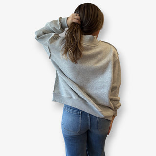 Person wearing a gray sweater with a white background