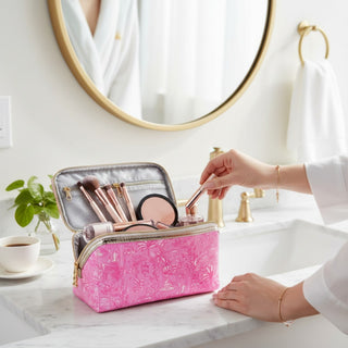 Lilly Pulitzer travel makeup bag in Palm Beach Playground pink print holding beauty essentials on bathroom vanity lifestyle view