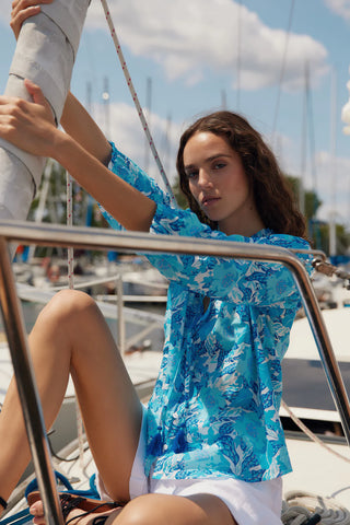 Detailed image highlighting 3/4 sleeves and button up closure of the Melissa Nepton Monica blouse in floral blue bloom with a ruffle collar and smocking bodice..