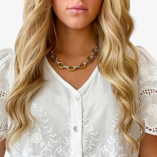 Mixed metal chain necklace with gold and silver oval links close-up on model neckline front view