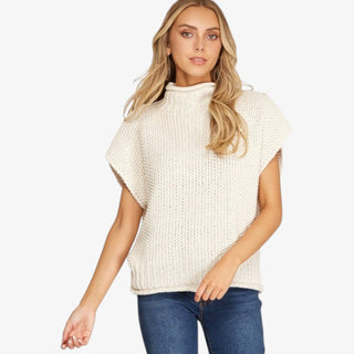 Woman wearing ivory mock neck knit sweater top with sleeveless design and relaxed fit