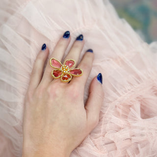 Oversized pink floral statement ring with gold trim and faceted crystal petals on hand boutique jewelry close-up view