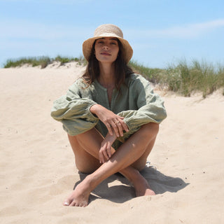     Oversized sage green linen blouse with lightweight fabric and band collar front seated view