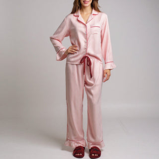Pink striped pajama set with red accents worn by a model on a gray background