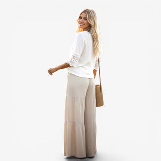 Woman wearing a white top and beige skirt with a straw bag on a white background