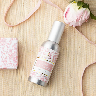 Peony Grapefruit room spray lifestyle image with pink floral fragrance bottle and peony flower flat lay view