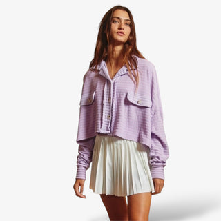 Woman wearing the Loose Fit Crop Shacket in light purple with a white pleated mini skirt on a white background 