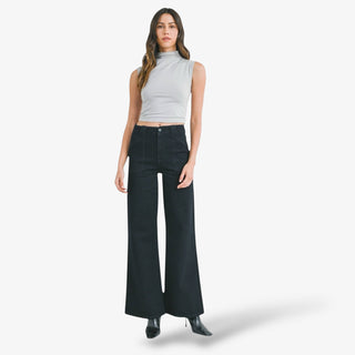 Woman wearing a gray sleeveless top and black wide-leg jeans on a white background