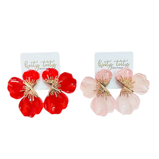 Red and pink floral earrings on branded cards against a white background