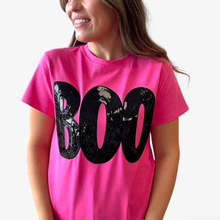 Person wearing a pink t-shirt with 'BOO' in black sequins on a plain background