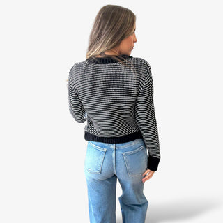 Woman wearing a black and white stripe sweater with jeans on a white background