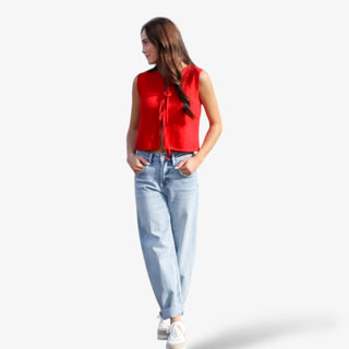Woman wearing a red sleeveless top and light blue jeans on a white background