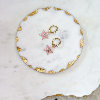 Pair of star-shaped earrings with pink centers and gold accents on a marble surface.