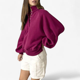 Person wearing a burgundy sweatshirt and white shorts on a white background